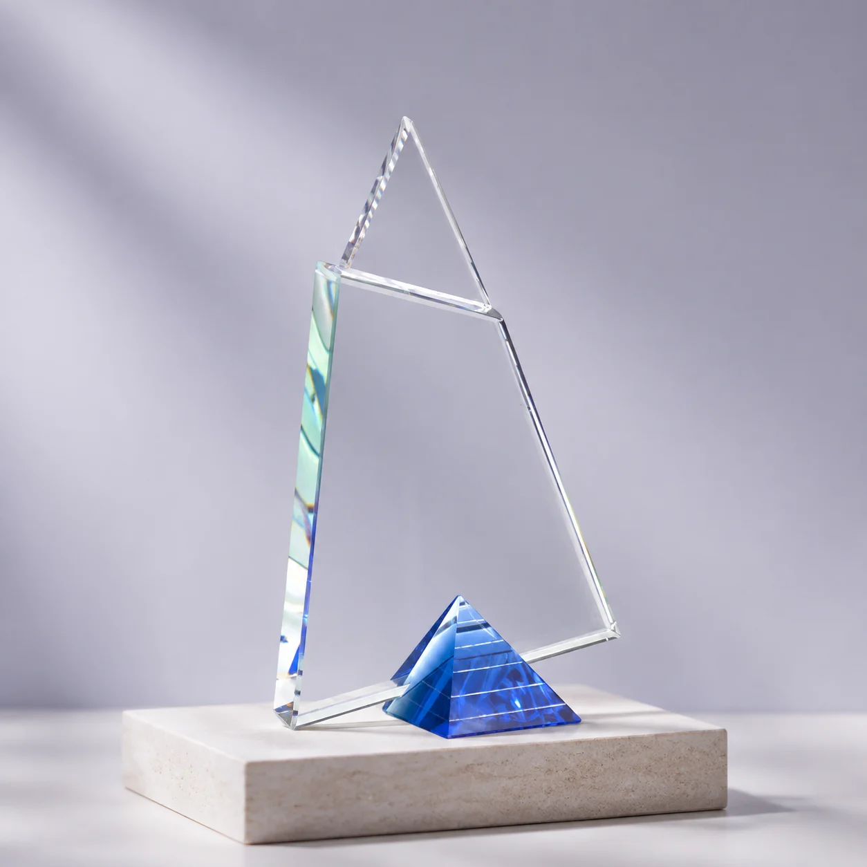 The Apex Award: a geometric clear crystal award with a blue pyramid base on a stone plinth